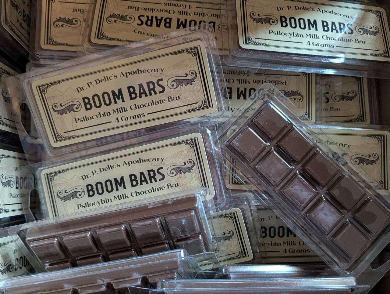 Stacked clear packages of Boom Bars psilocybin milk chocolate bars with vintage-style apothecary labels.