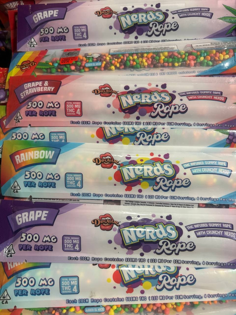 Multiple packages of 500mg THC-infused gummy ropes mimicking Nerds Rope candy in various flavors.