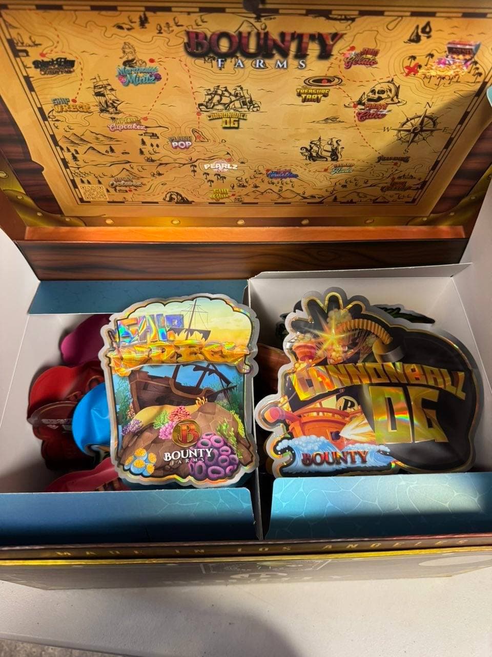 Open pirate treasure chest box with a map lid and holographic Bounty Farms pouches.